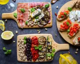 Ein köstlicher italienischer Abend mit Aufschnitt, Käse, gegrilltem Gemüse, Bruschetta und Pistazien. Perfekt für Genießer!
