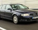 Ciemnogranatowe Audi A4 B6 2.0 Avant pędzi autostradą. Kierowca skupiony na drodze.