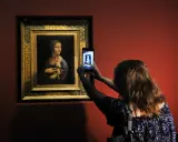 Dama z łasiczką w muzeum, gdzie jest? Kobieta robi zdjęcie słynnego obrazu telefonem.