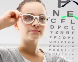 Dziewczynka z okularami przed tablicą Snellena. Czy -1.25 to duża wada wzroku?
