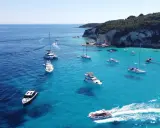Båtar i turkost vatten vid en klippig kust, en idyllisk vy från Paxos, Grekland.