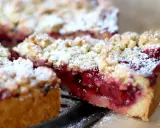 Ein saftiger Kirschstreuselkuchen, bestäubt mit Puderzucker, wartet darauf, genossen zu werden.