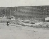 Edificio masivo de apartamentos en construcción, con obreros y vehículos en el sitio. Imagina cómo se veía cuando se inventó el cemento.