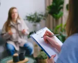 Psychologia kliniczna w praktyce: terapeuta notuje objawy pacjentki, która opowiada o swoich problemach.