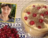 Kobieta uśmiecha się obok deseru z nasionami chia i porzeczkami. Nasiona chia – właściwości odchudzające w pysznej formie.