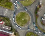 Widok z lotu ptaka na wjazd na rondo, gdzie samochody płynnie się poruszają.