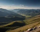 Widok na pasmo górskie, gdzie widać, jak daleko widzi ludzkie oko. Dolina z polami i lasami, otoczona łagodnymi wzgórzami.