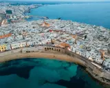 Vista aerea del centro storico di Gallipoli, con case bianche, mare turchese e un arco sul lungomare. Scopri cosa vedere a Gallipoli centro storico.