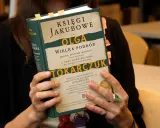 Osoba trzyma książkę "Księgi Jakubowe" Olgi Tokarczuk, z zakładkami w różnych kolorach.