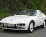 Weißer Porsche 924 fährt auf einer Straße. Der geringe porsche 924 verbrauch macht ihn zu einem sparsamen Klassiker.