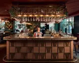 En glad bartender vid en elegant cocktail bar i Stockholm, med drinkar och glas på rad.