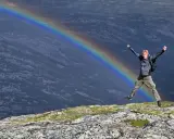 Radosny turysta skacze na tle tęczy w górach. To wspaniałe wspomnienie z Norwegii z dziećmi.