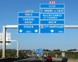 Znaki drogowe na autostradzie we Francji wskazują drogę do Lille, Paryża, Cambrai, Douai i Denain.