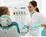 Uśmiechnięta dentystka w rękawiczkach rozmawia z pacjentką. Może właśnie omawia antybiotyk na zęba.