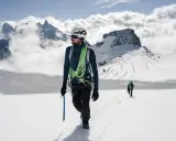 Dwóch alpinistów na ośnieżonym szczycie. Jeden z nich, z czekanem w dłoni, pokazuje, jak dobrać czekan do wspinaczki.