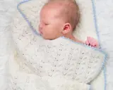 Sover sött i en stickad filt. Att knyta sjal bebis är ett mysigt sätt att hålla dem varma.
