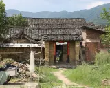Maison en terre crue, toits de tuiles anciennes, montagnes en arrière-plan. Le prix d'une telle demeure est abordable.