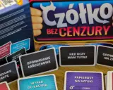 Karty do gry "Czółko bez cenzury" leżą na stole. Widać napisy: "Opowiadanie łańcuchowe", "Hej! Oczy mam tutaj!", "Opowiadanie na małpę", "Wypad do kasyna".