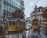 Lisbona, Portugalia. Żółte tramwaje na brukowanej ulicy, ludzie i samochody. Ceny w Portugalii mogą być różne, ale widok wart jest każdej ceny.