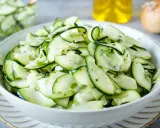 Frischer Salat aus dünn geschnittenen Zucchinischeiben, mariniert mit Kräutern und Öl. Perfekt, um Zucchini roh zu essen.