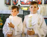Dwóch chłopców w albach trzyma ozdobione świece. Widać, jak ozdobić świecę komunijną, by była piękna na tę wyjątkową okazję.