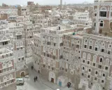 Ein malerisches arabisches Haus mit kunstvollen weißen Verzierungen und vielen Fenstern, eingebettet in eine Stadt mit ähnlicher Architektur.