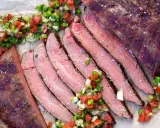 Saftiges, in Scheiben geschnittenes Flank Steak Deutsch, garniert mit frischer Salsa.