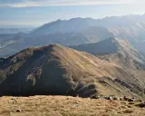 Widok na pasmo górskie Tatr. W oddali widać kolejne grzbiety górskie, a na pierwszym planie ścieżki i kamienie. Trasy Tatry zachęcają do wędrówki.