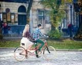Para co to? Para na rowerze typu tandem przemierza brukowaną uliczkę w jesiennym mieście.