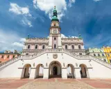 Zamość rynek: Ratusz z imponującymi schodami i kolorowe kamienice pod błękitnym niebem.