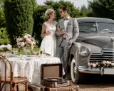 Para młoda w stylu retro przy stole z kwiatami i starym samochodem. Wesele w stylu retro z winylowym gramofonem.