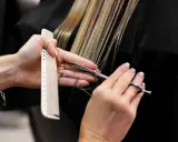Manos de estilista cortando cabello rubio con tijeras y peine. Decisión: cortar el pelo en seco o mojado.