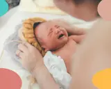 Un recién nacido no duerme, llora desconsoladamente mientras una mano le acaricia la cabeza.