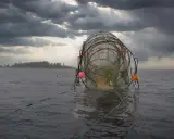 Fiskeredskap i vattnet, redo för att fiska lax. Mörka moln hänger över en grå himmel.