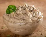 Pyszna pasta z tuńczyka w szklanej miseczce, doprawiona pieprzem i udekorowana gałązką natki pietruszki. Idealna na kanapki.