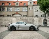Silberner Porsche GT4 vor historischer Kulisse. Die technischen Daten dieses Sportwagens sind beeindruckend.