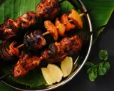 Brochettes de poulet grillées, marinées et savoureuses, avec oignons et poivrons, servies sur une feuille de bananier avec des quartiers de citron.