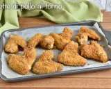 Alette di pollo al forno dorate e croccanti, guarnite con rosmarino fresco, pronte per essere gustate.