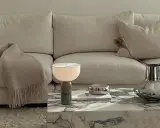 En soffa med en filt och kuddar. På soffbordet står en marmorerad lampa, en bok, en silverfärgad skål och en vas med torkade blommor. Ett inreda hem med stil.