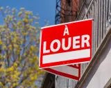 Panneau "À louer" rouge vif, un signe d'espoir pour comment trouver un logement rapidement. Arbre fleuri en arrière-plan.