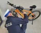 Policjant sprawdza, czy na rower elektryczny trzeba mieć prawo jazdy. Pomarańczowy rower z sakwą na kierownicy.