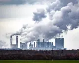 Rauchschwaden steigen aus einem Kraftwerk auf und symbolisieren die historischen CO2-Emissionen, die die Umwelt belasten.