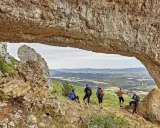 Senderismo Navarra: grupo de excursionistas admira un paisaje montañoso desde debajo de un arco de roca natural.