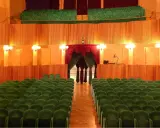 L'arena della regina cattolica, un teatro con poltrone verdi e sipario rosso, attende il pubblico.