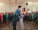 Para młoda tańczy w deszczu konfetti, a goście weselni, jakby słuchali ostrych przyśpiewek weselnych, nagrywają ten moment.