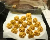 Piped dollops of golden-brown sauce arranged on white parchment paper, with a roasted dish in the background.