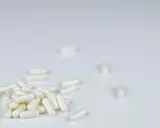 Białe kapsułki leżą na białym tle. Czy to anapran na ból głowy, czy coś innego?