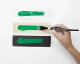 Grüne Acrylfarben-Streifen auf weißem, Holz- und schwarzem Untergrund. Perfekt für den Modellbau, um die Deckkraft zu testen.