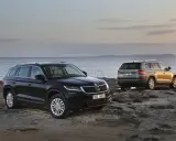Dwa SUV-y Skoda Kodiaq 2024 na skalistym wybrzeżu. Jeden czarny, drugi w kolorze złota.
