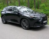 Elegancki, czarny Lexus NX 350h na tle leśnej drogi.